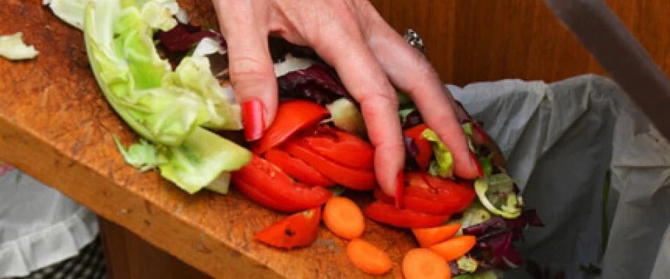 Chef disposing of vegetable scraps in bin