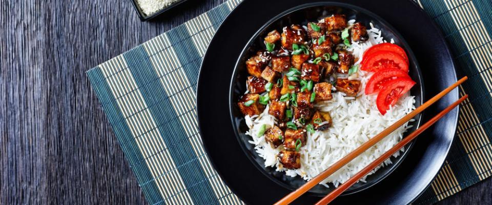 Teriyaki tofu with rice, green onion, and sliced tomato in bowl