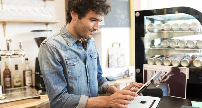 Café worker using cloud point of sale system to take order