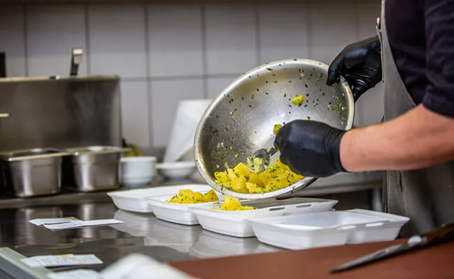 Chef preparing takeaway dishes in kitchen
