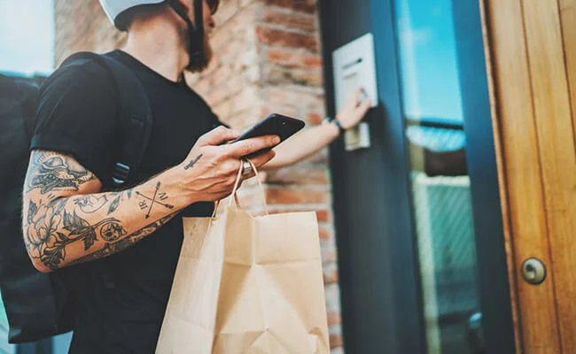 Tattooed food delivery rider ringing electronic doorbell