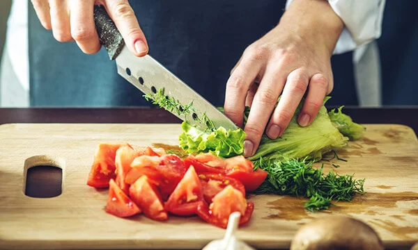 chef in black apron chopping vegetables
