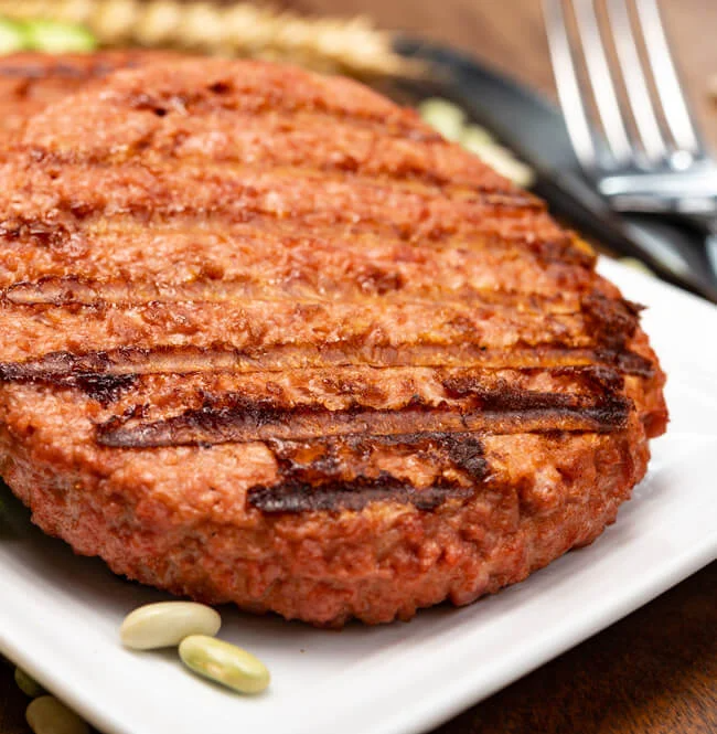 Grilled plant-based meat patties on plate with vegetables