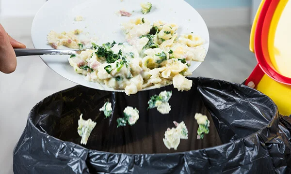 Edible food being scraped off plate into bin