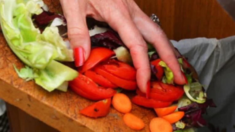 Chef disposing of vegetable scraps in bin