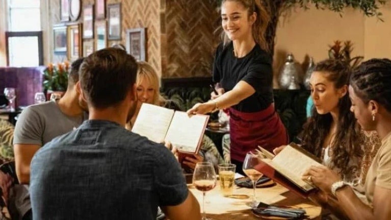 Waitress serving simple menu to table of customers