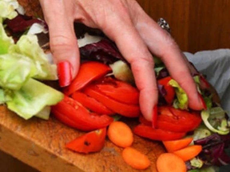 Chef disposing of vegetable scraps in bin