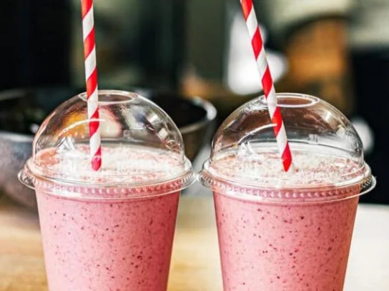 Two fruit smoothies on table with red and white straws