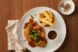 A perfectly crumbed chicken schnitzel, plated on a bed of lusciously silky and creamy Maggi Mash with coleslaw and a lemon we